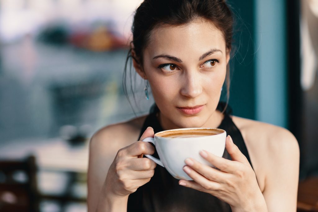 Refined Woman Enjoying Cappuccino or Latte on a vibrant, colorful background indoors.